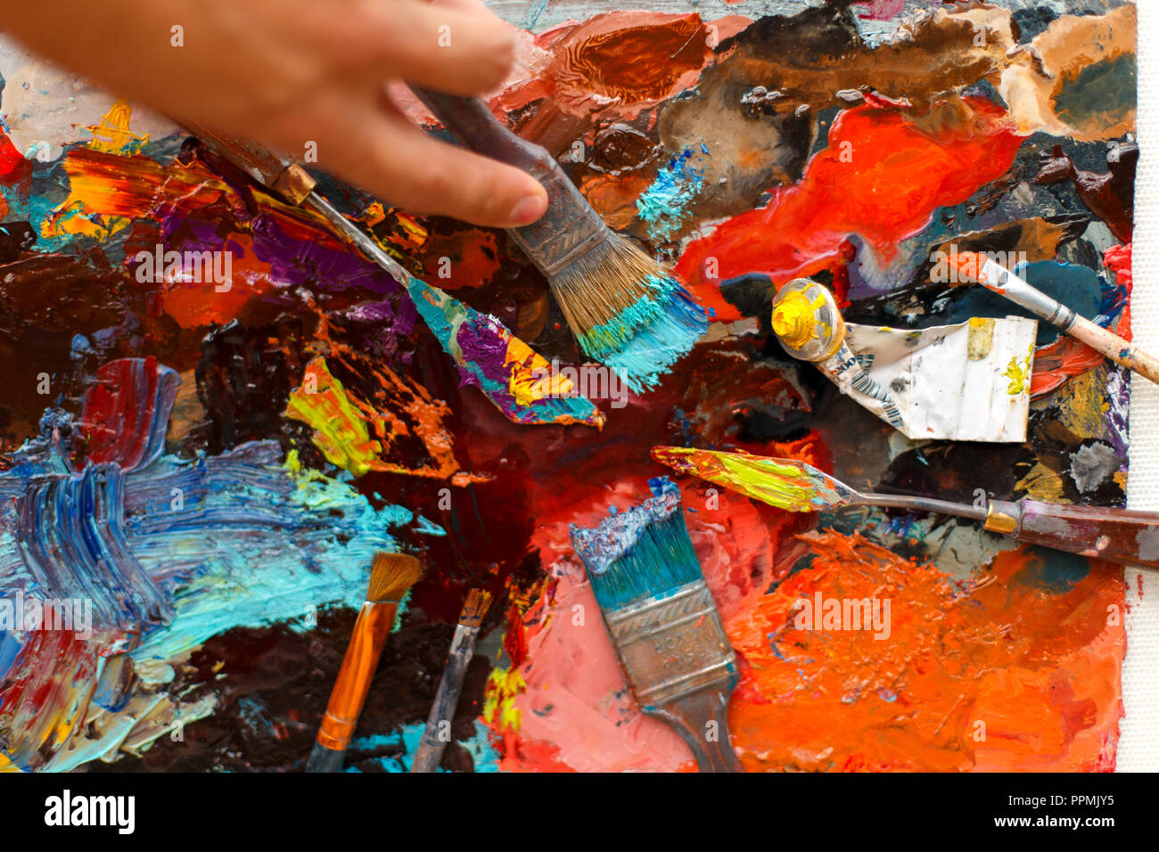 set of an artist's tool on a background with oil paint. Man's hand