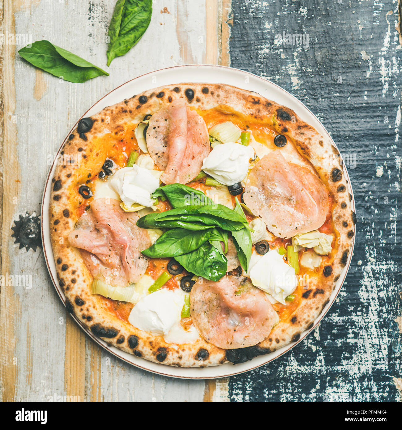 Freshly baked pizza with ham, artichokes, cheese, basil, square crop