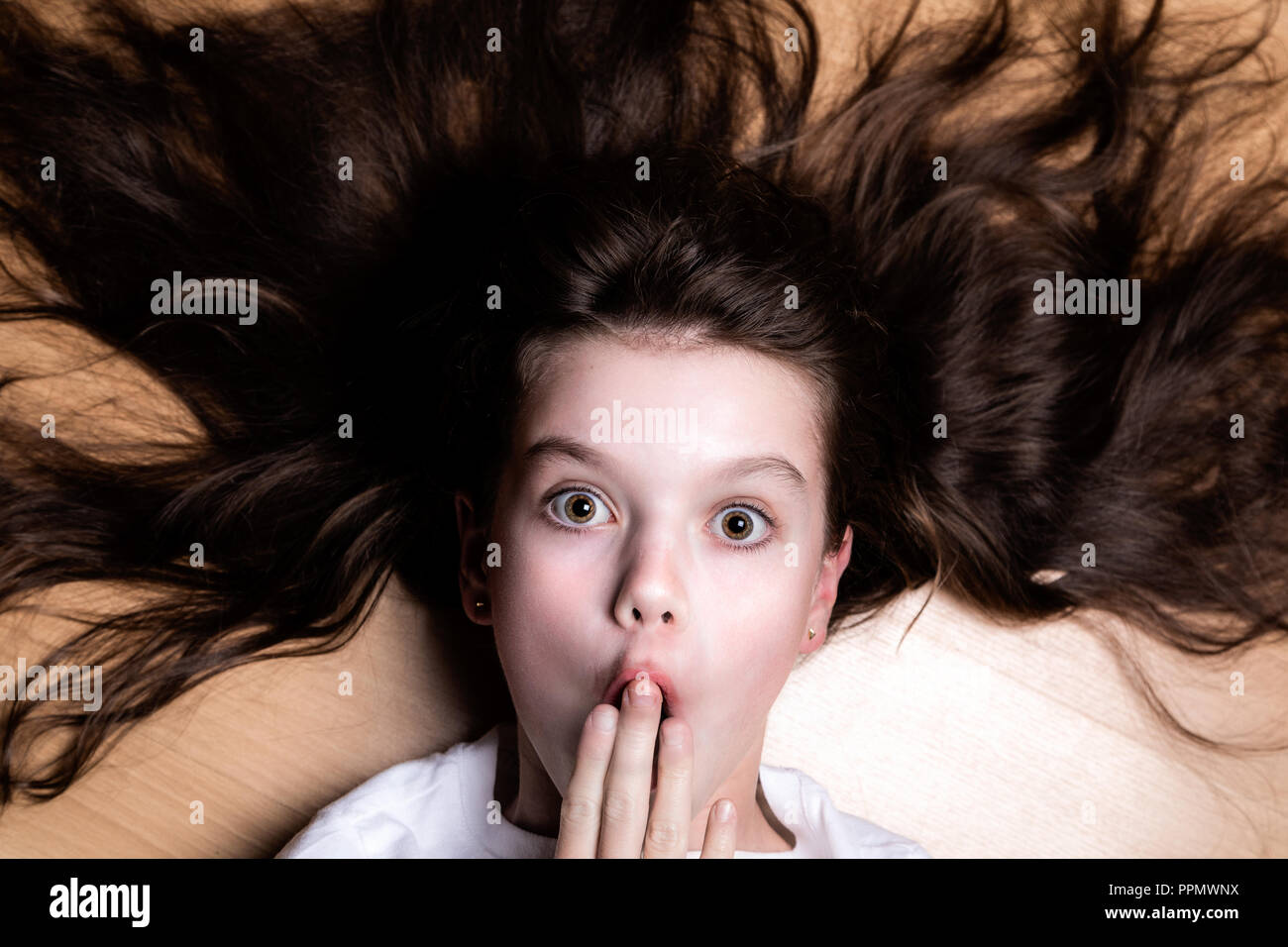 Young girl with shocked expression and hair spread out hires stock