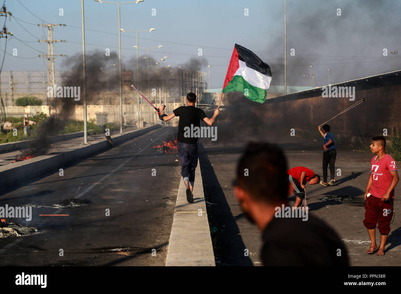 Gaza. 26th Sep, 2018. A Palestinian protester holds a Palestinian flag during clashes with Israeli troops after a protest at Erez crossing near the border with Israel, northern Gaza Strip, on Sept. 26, 2018. Credit: Stringer/Xinhua/Alamy Live News Stock Photo