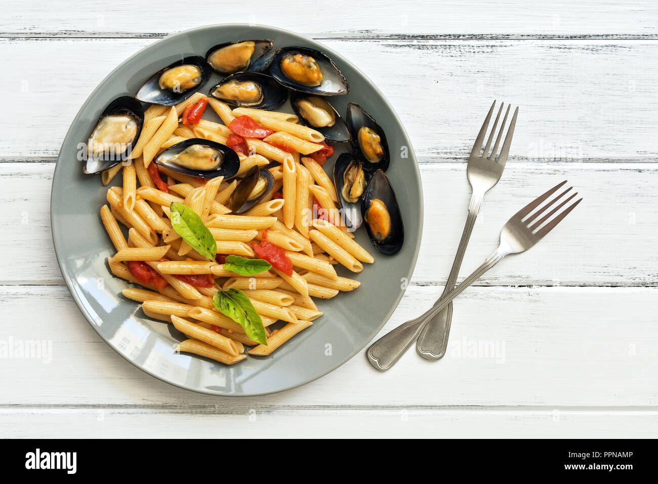 Penne pasta with mussels on a white wooden rustic table. Macaroni with seafood. Top view, copy space Stock Photo