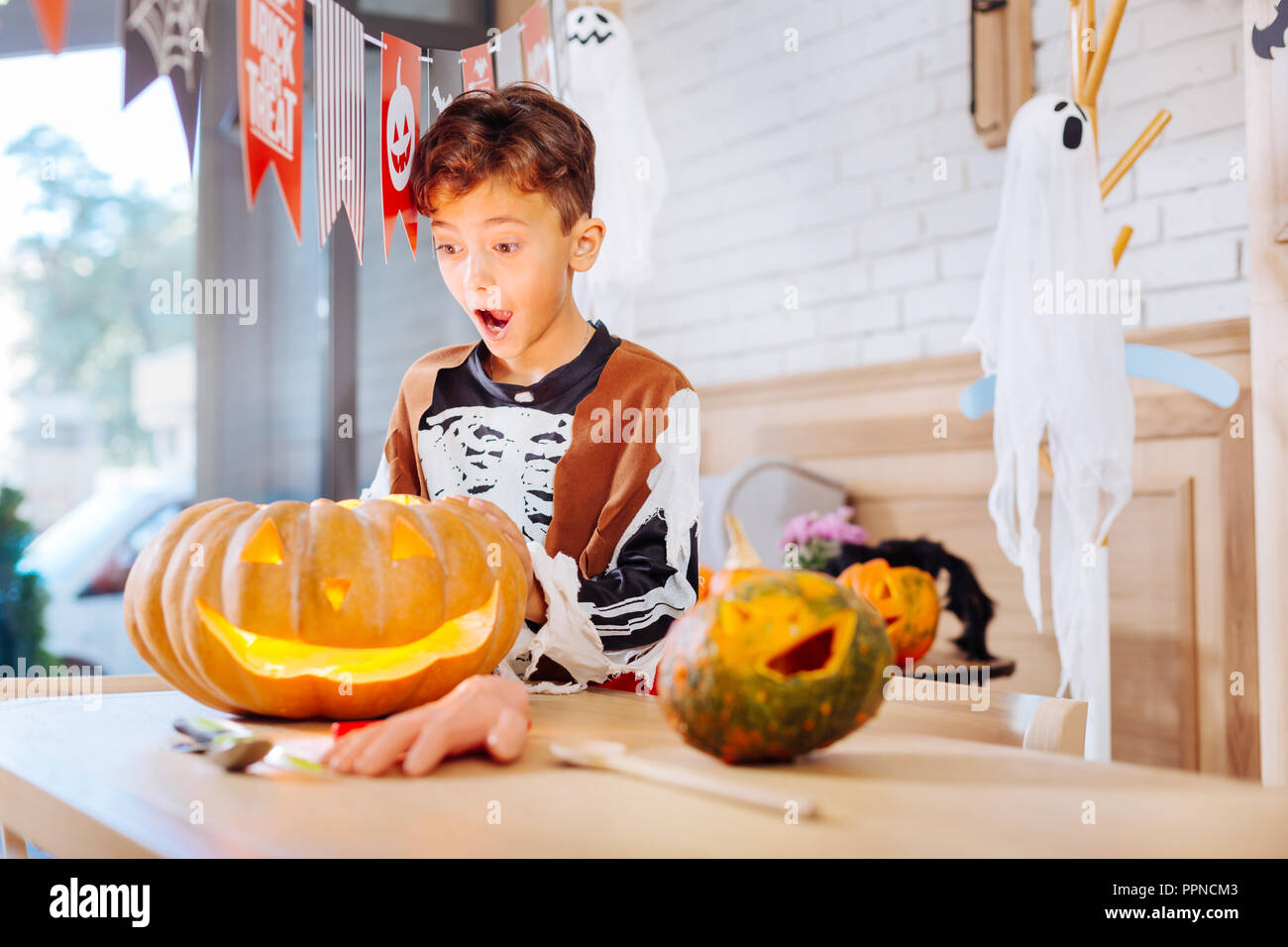 Schoolboy wearing skeleton costume for Halloween standing near pumpkin Stock Photo