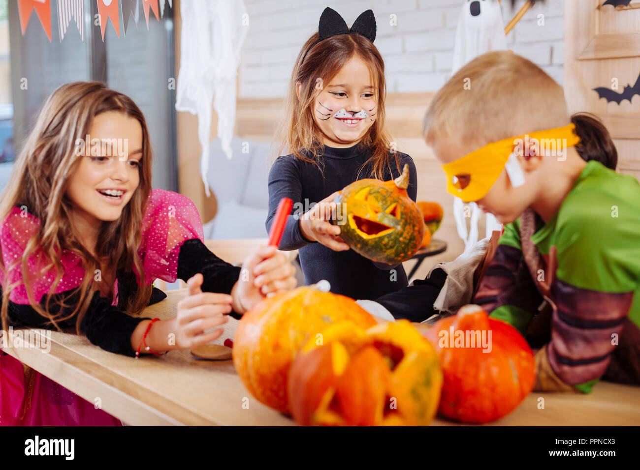 Cute smiling girl wearing cat costume holding little carved Halloween ...