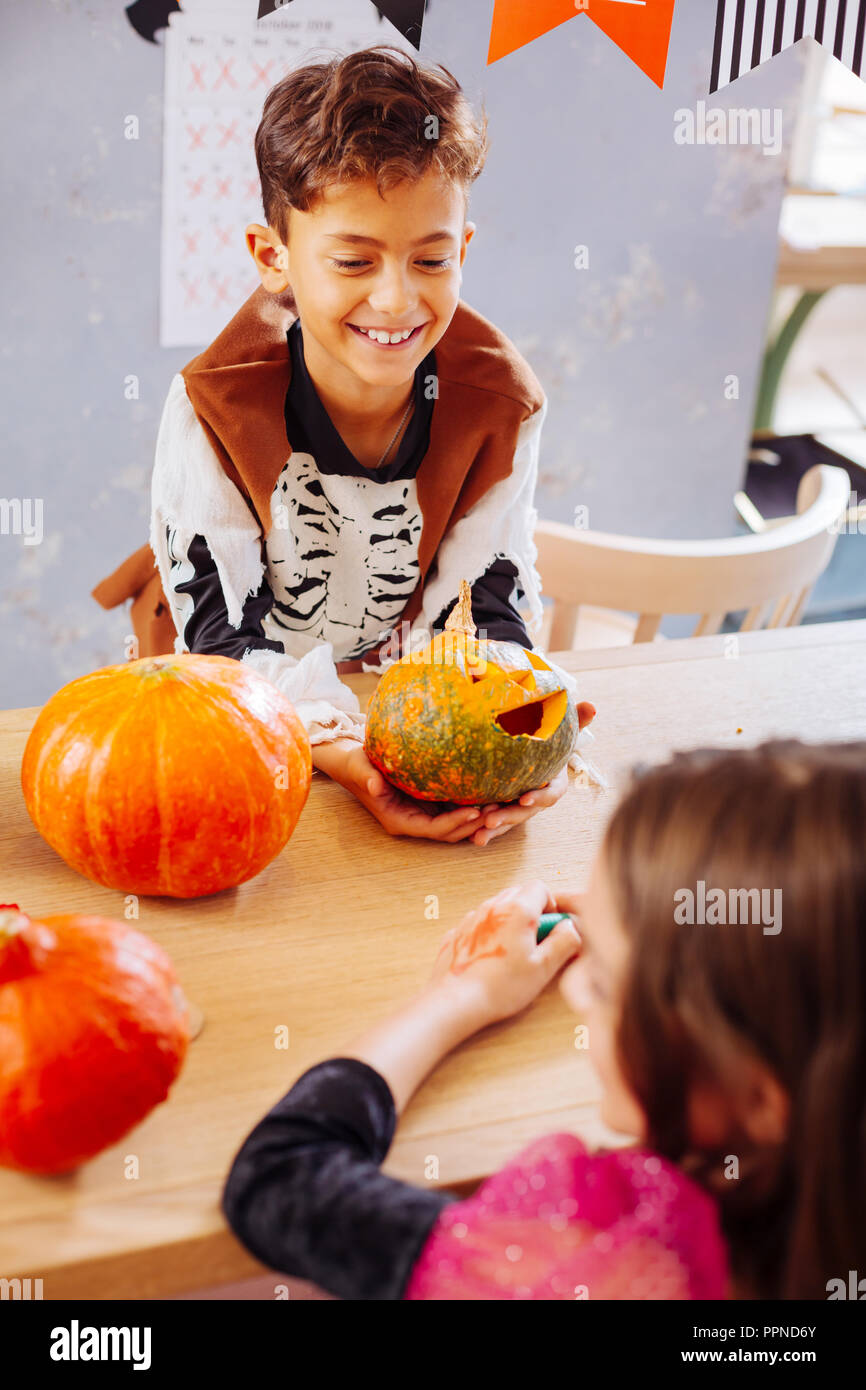 Curly dark-haired smiling boy wearing skeleton costume for Halloween Stock Photo