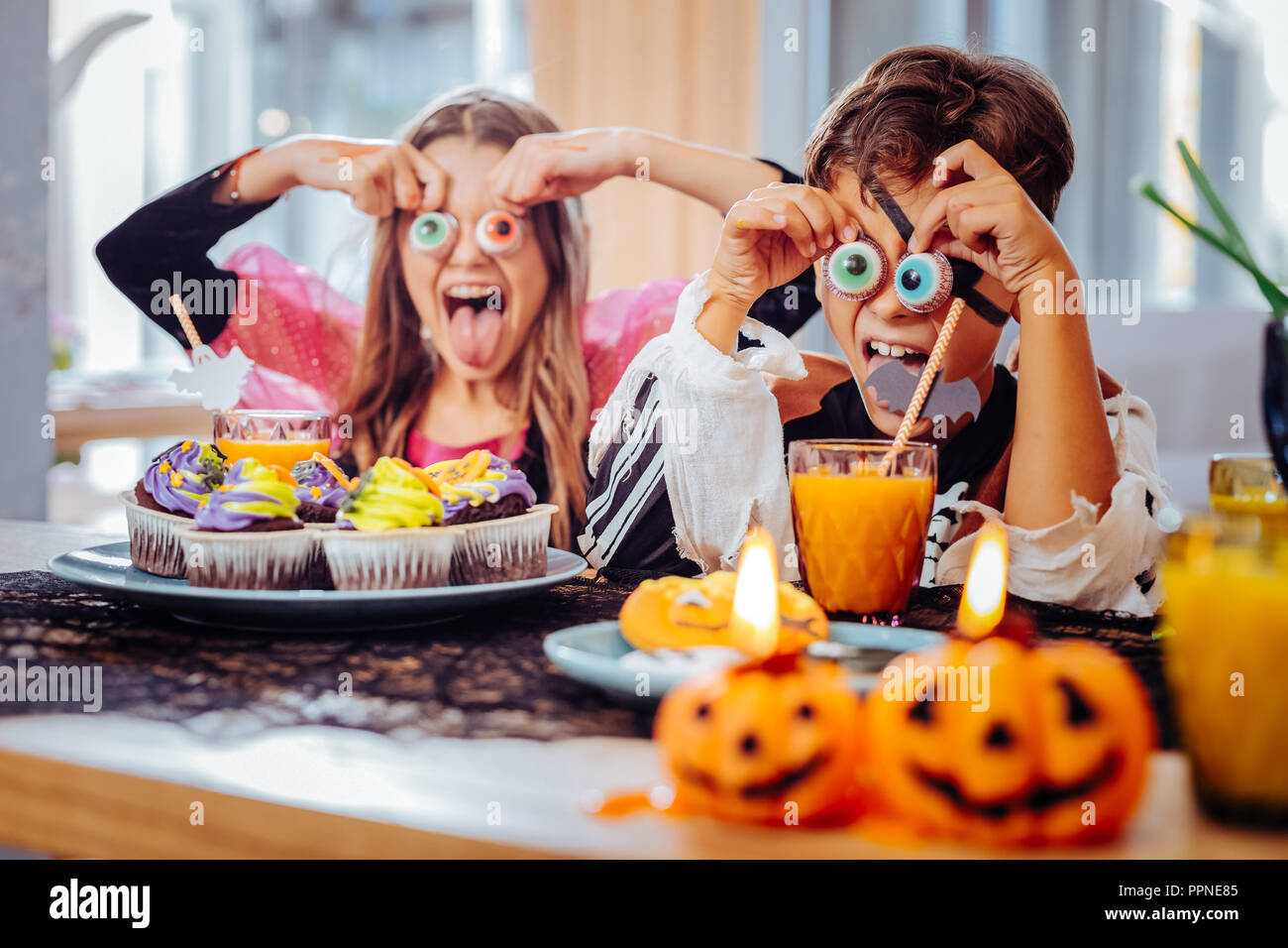 Brother and sister having Halloween party eating thematic cookies Stock Photo