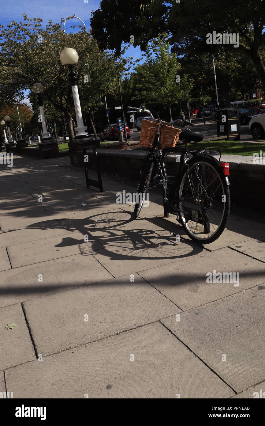 A black ladies bicycle is secured to a bike stand on the wide pavement of Lord Street in Southport the strong autumn sunshine creates long shadows Stock Photo Alamy