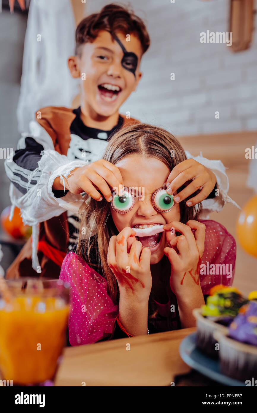 Brother and children feeling funny while eating thematic sweets for Halloween Stock Photo