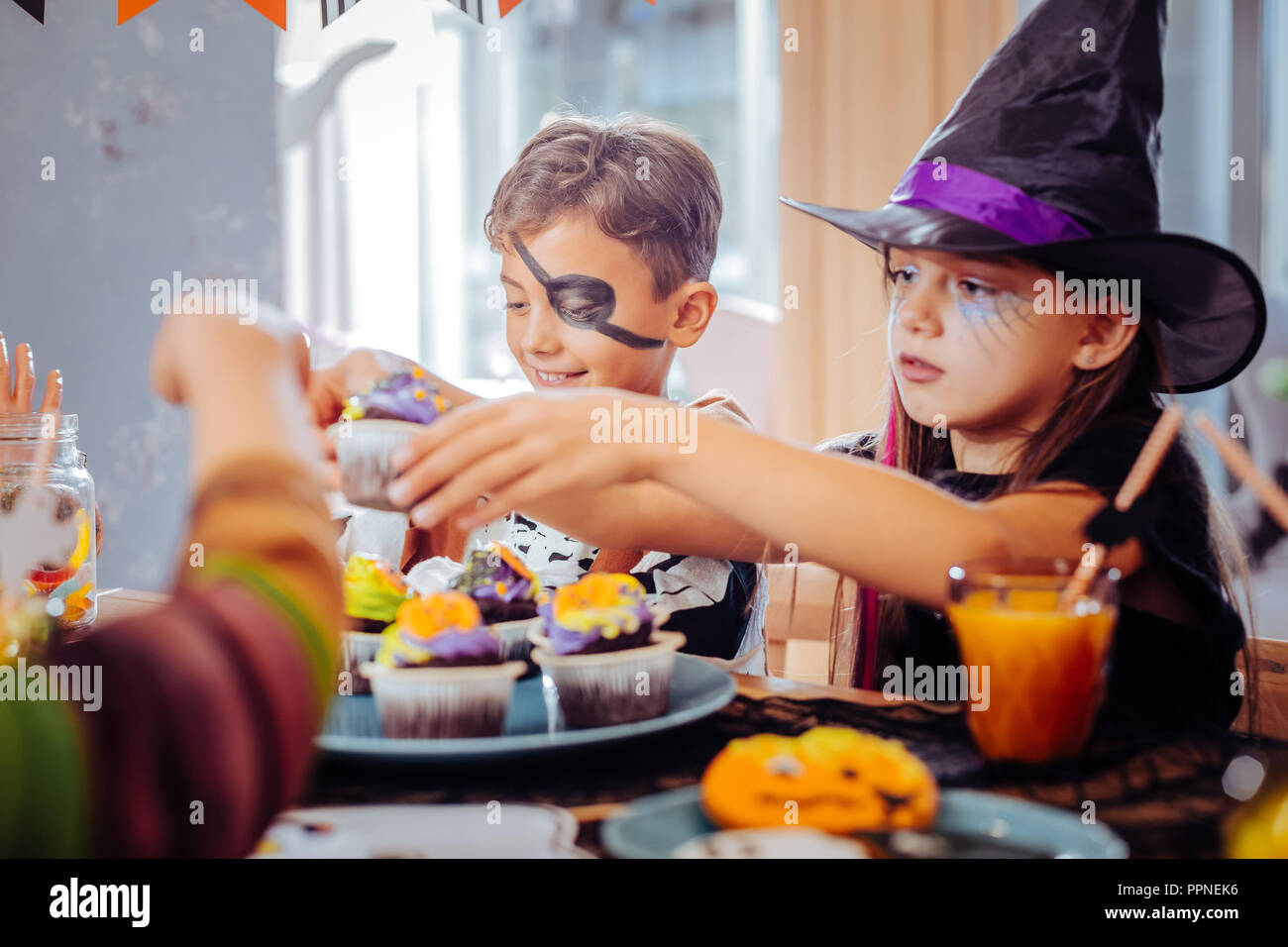 Children celebrating Halloween at kindergarten eating thematic sweets Stock Photo