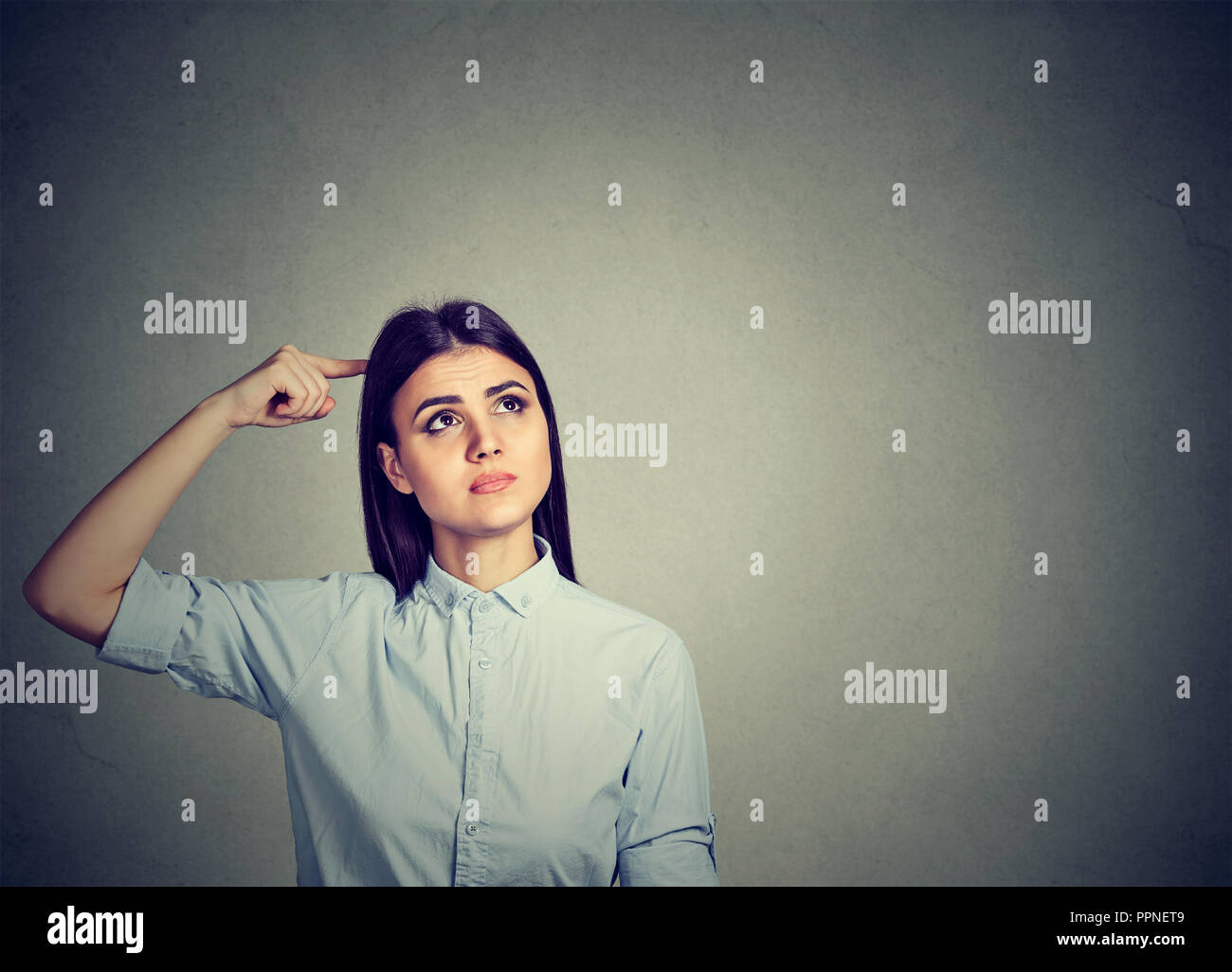 Young puzzled brunette woman scratching head in perplexion looking away Stock Photo