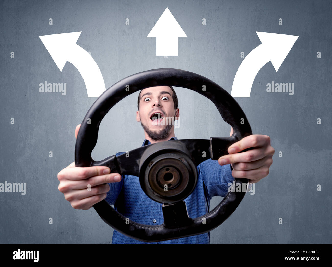 Young man holding black steering wheel with three arrows above his head