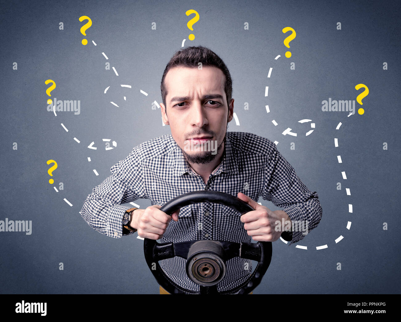 Young man holding black steering wheel with question marks around him