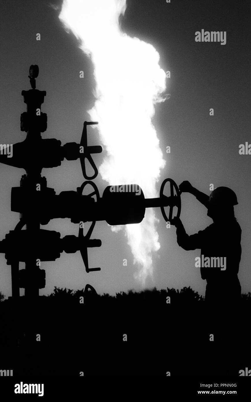Worker adjusts valve at an Oklahoma oil field site, USA Stock Photo