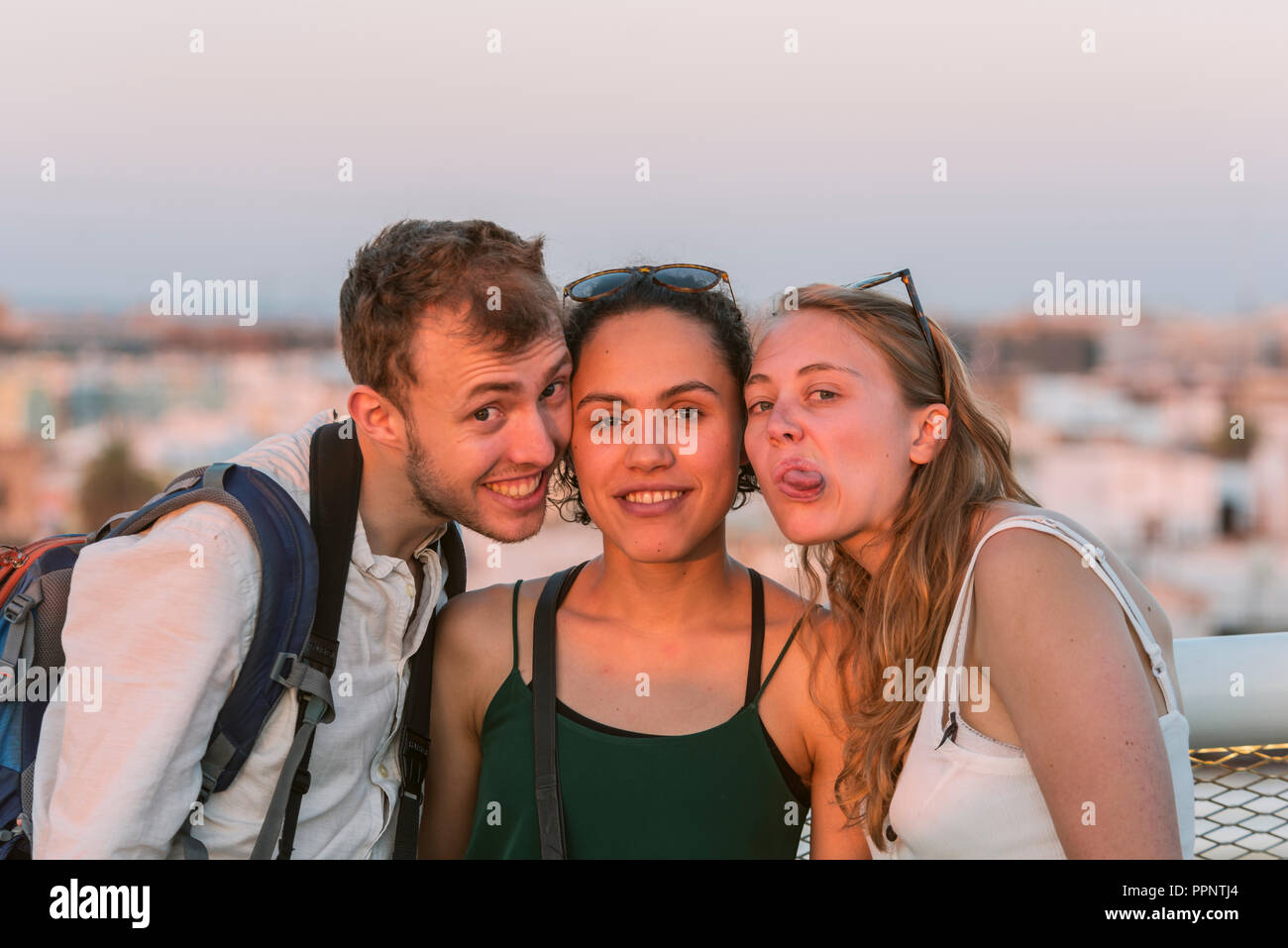 Two young women and young man look into the camera, make faces, friends, Plaza de la Encarnacion, Sevilla, Andalusia, Spain Stock Photo