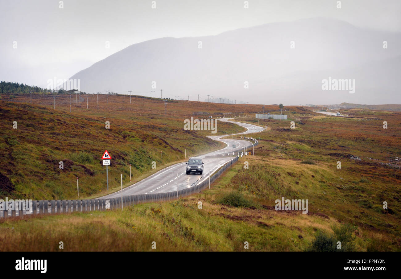 CARS TRAVELLING ON THE A835 NEAR ULLAPOOL SCOTLAND RE BENDS IN ROAD THE HIGHLANDS DRIVING REMOTE LOCATIONS WET ROADS SCOTTISH UK Stock Photo