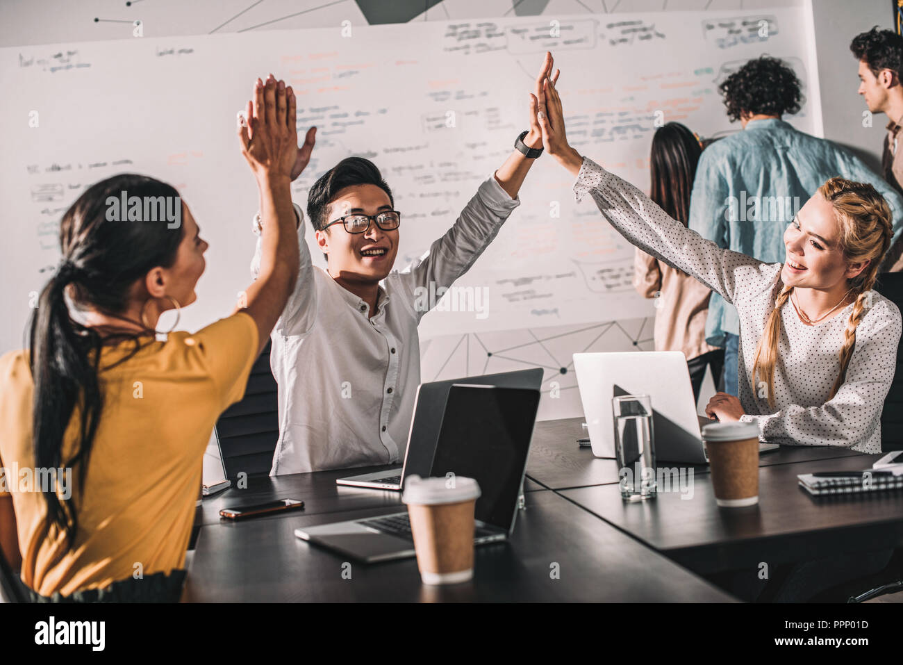 young asian businessman taking high fives to female colleagues at modern office Stock Photo