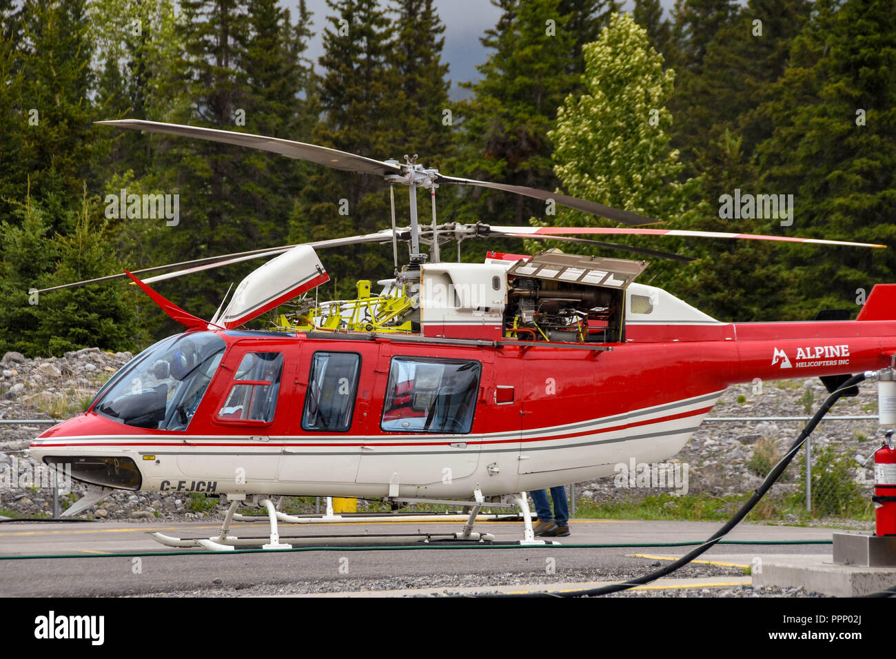 CANMORE, ALBERTA, CANADA - JUNE 2018: Bell 407 helicopter operated by Alpine Helicopters in Canmore. Its engine cover is open for maintenance. Stock Photo
