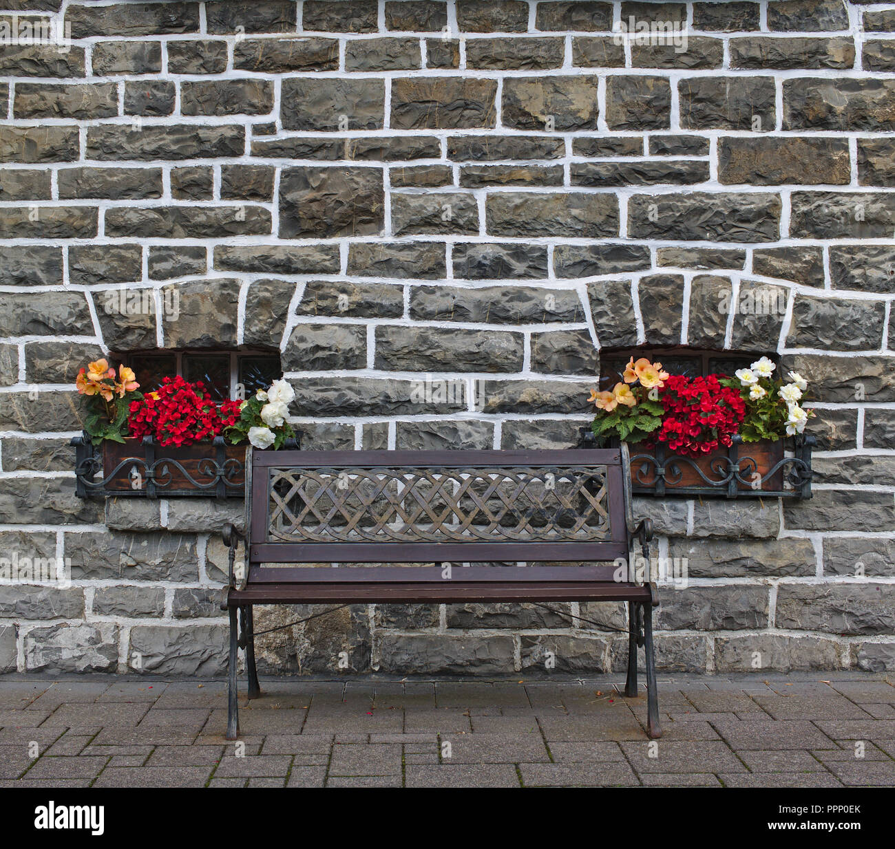 Wooden bench in front of old gray stone wall with two small windows ...