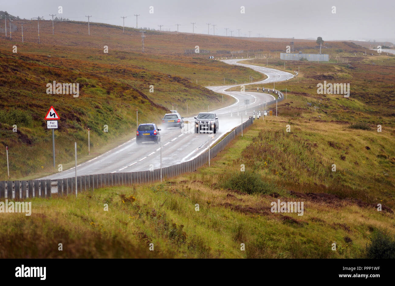 CARS TRAVELLING ON THE A835 NEAR ULLAPOOL SCOTLAND RE BENDS IN ROAD THE HIGHLANDS DRIVING REMOTE LOCATIONS WET ROADS SCOTTISH UK Stock Photo