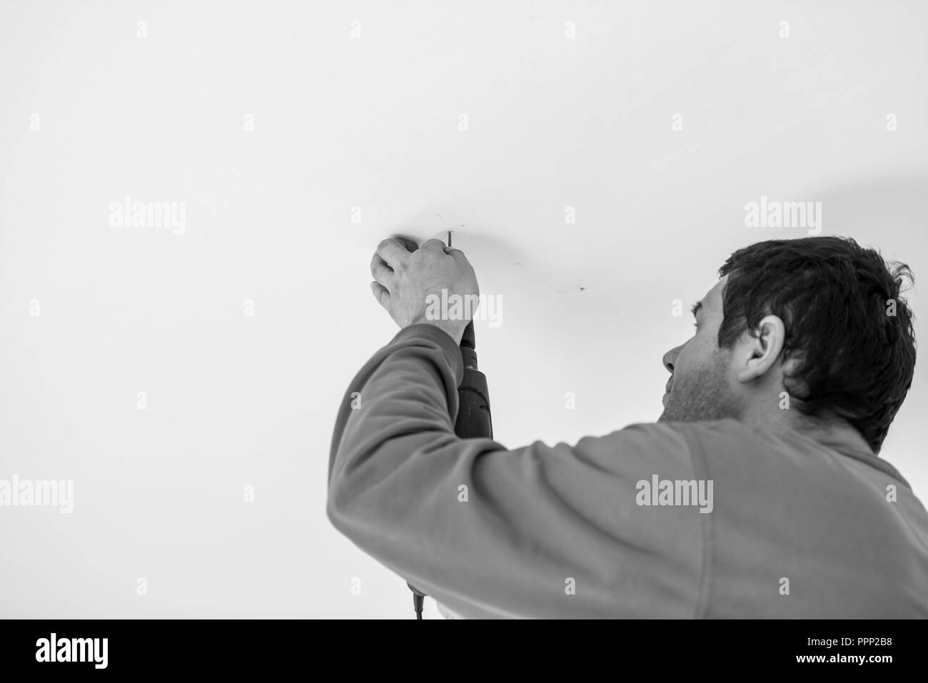 Greyscale Image Of A Workman Using A Handheld Electric Drill To