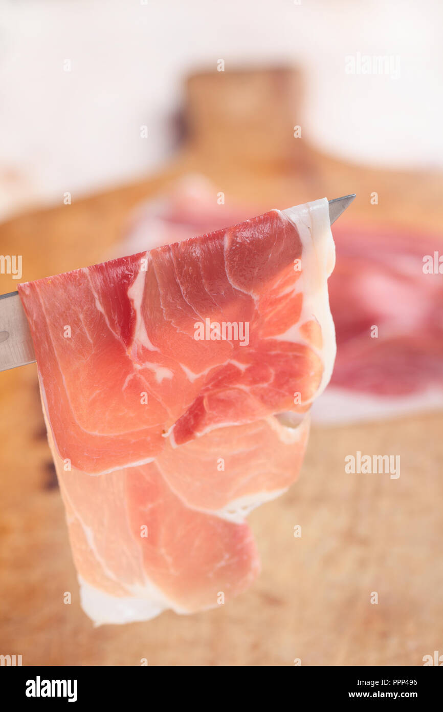 Thin slice of Prosciutto on a knife Stock Photo