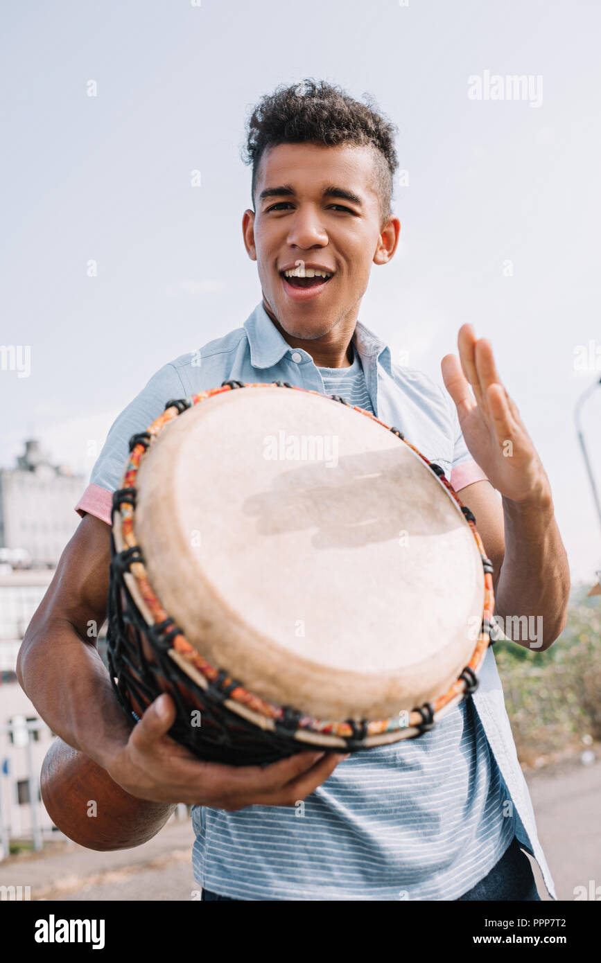 Young and happy african american street musician with djembe performing on  sunny city street Stock Photo - Alamy
