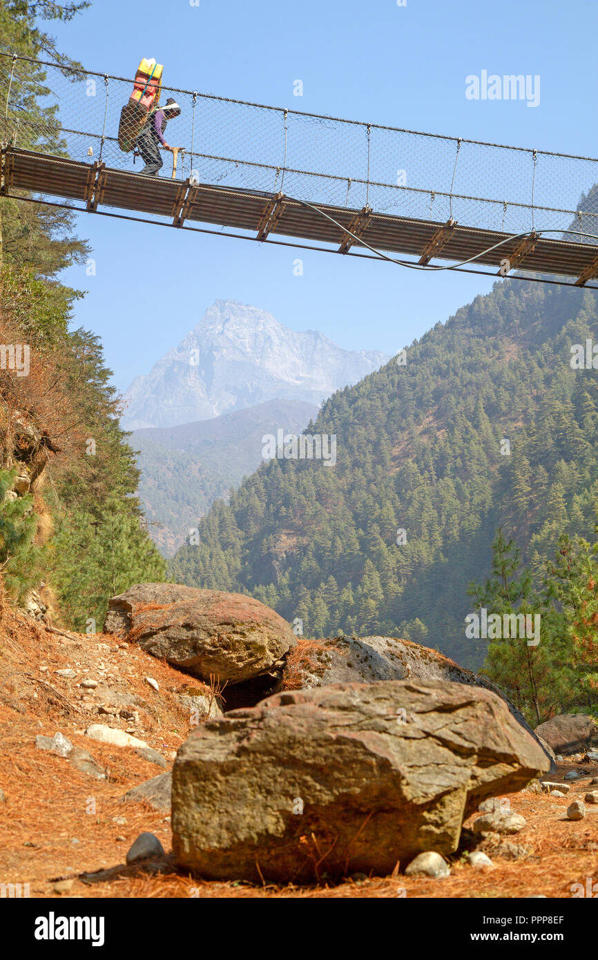Porter crossing a suspension bridge over the Dudh Kosi on the trail to