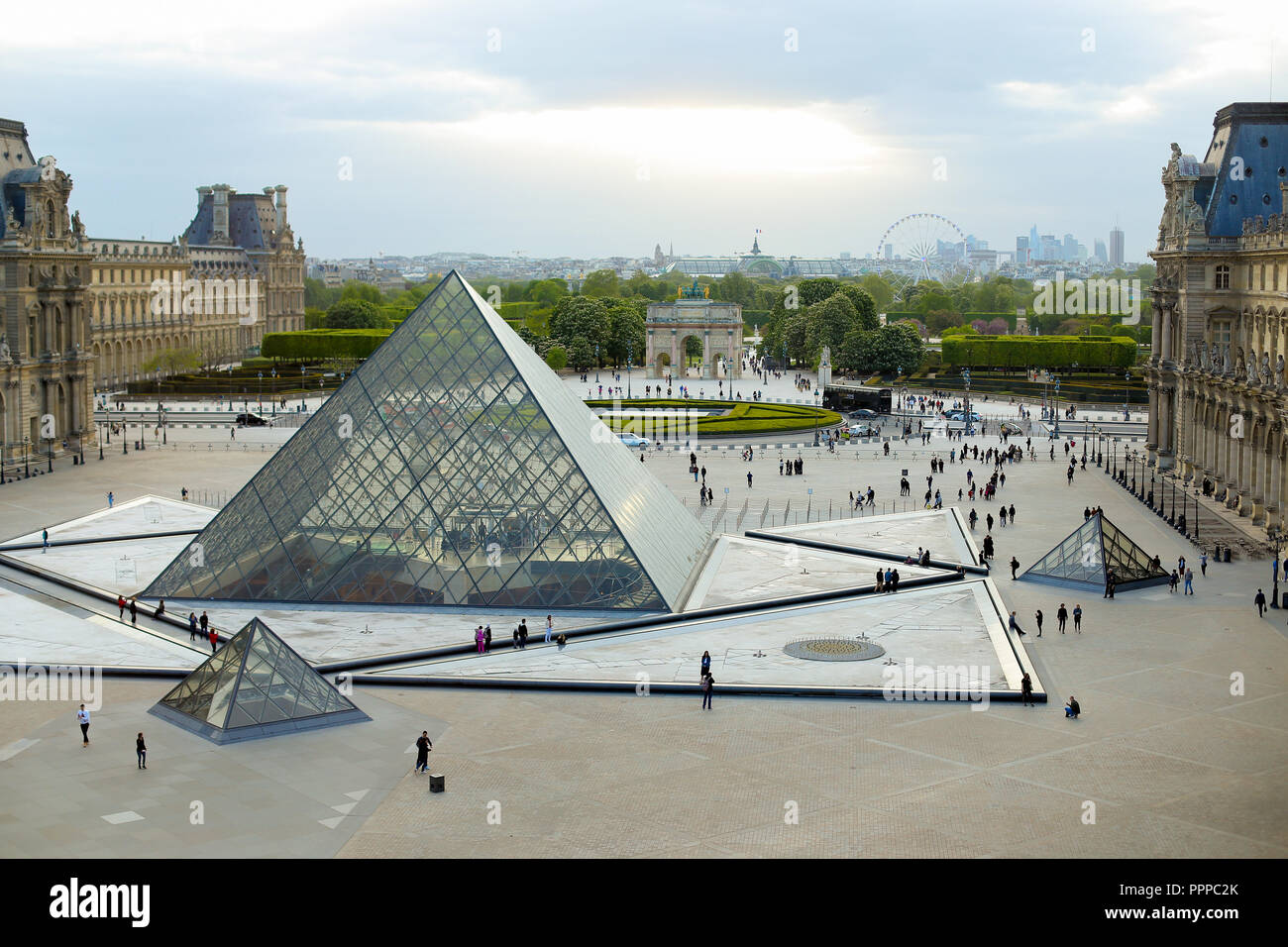 Glass pyramid and many tourists walking in Louvre, Paris, France ...