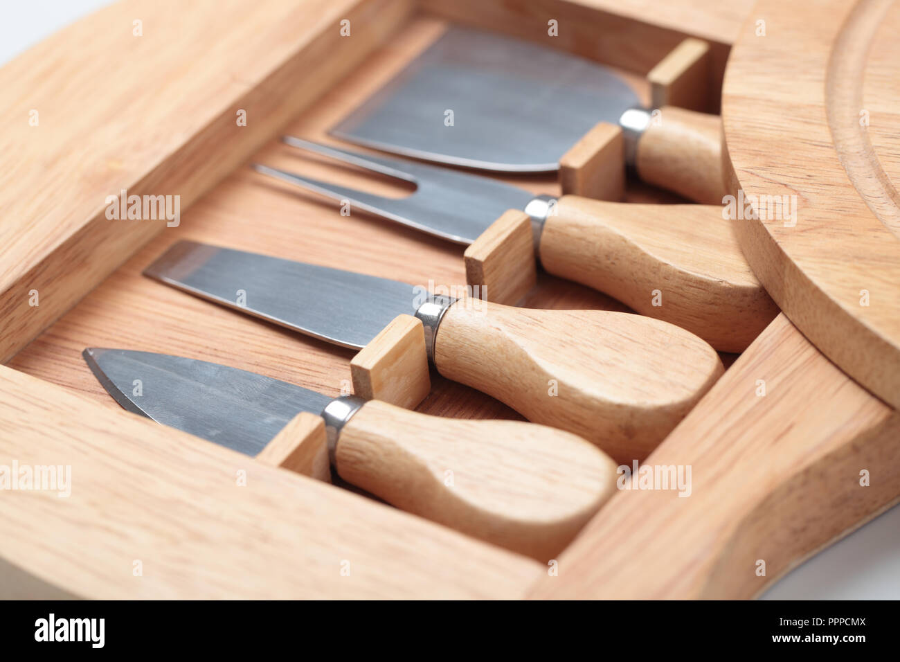 Set of four cheese knives and wooden cutting board Stock Photo Alamy