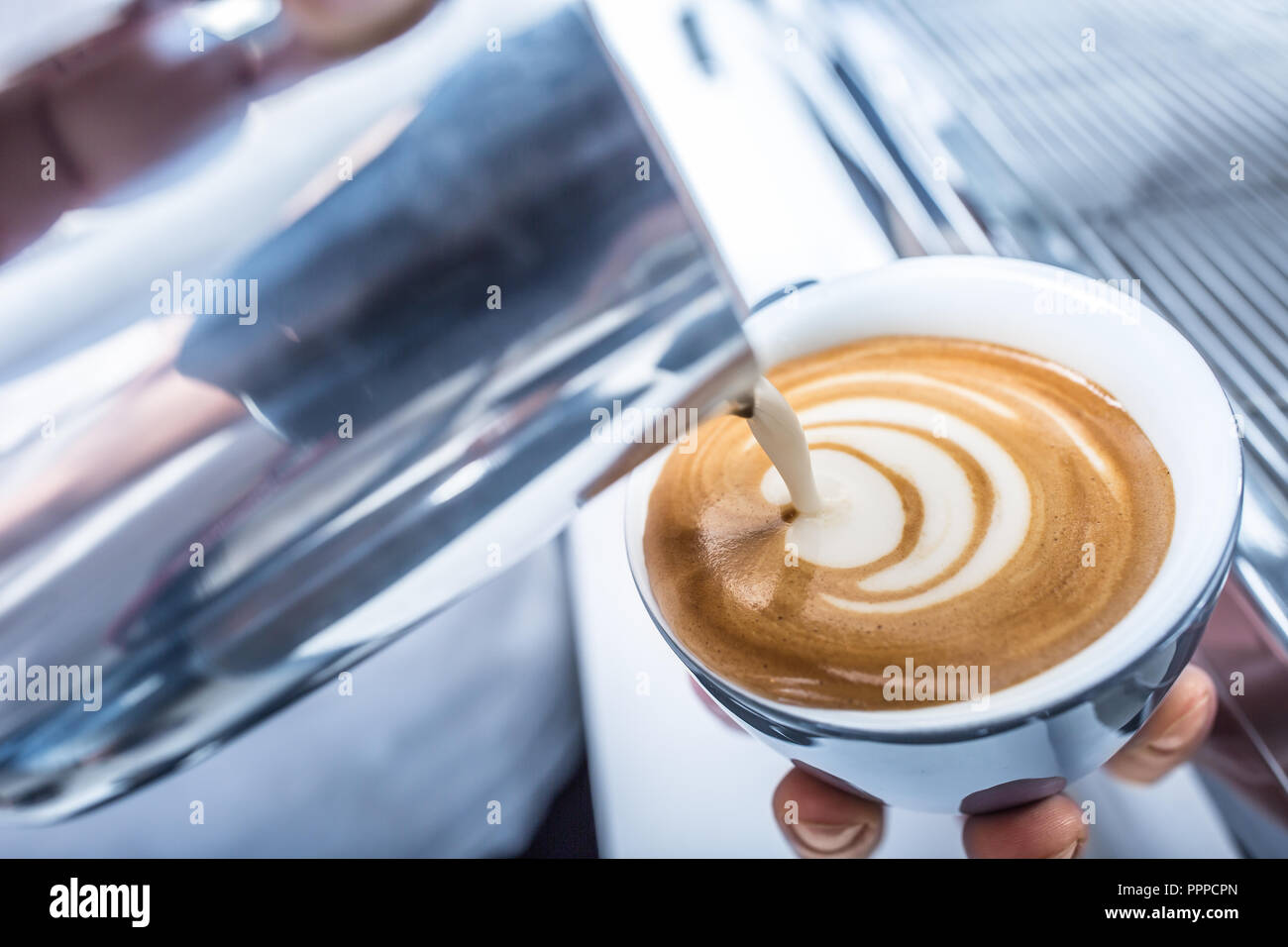 Barista making art coffee and pouring milk in to cup. Stock Photo