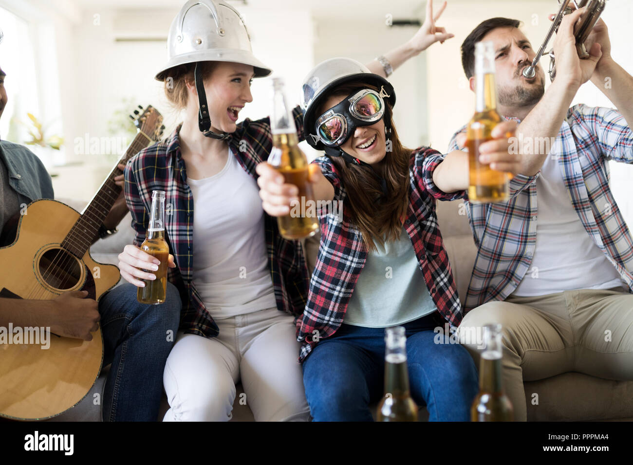 Group of friends playing guitar and partying at home Stock Photo