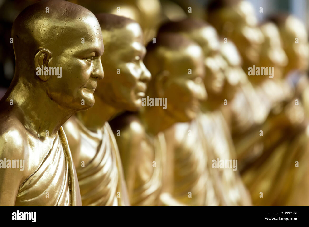 Side view of row of golden shiny statues of monks Stock Photo Alamy