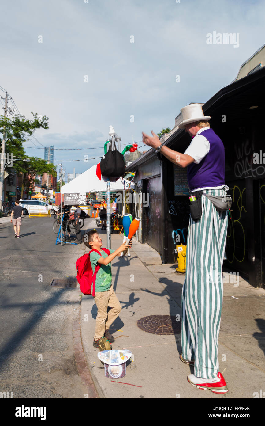 TORONTO, ON, CANADA - JULY 29, 2018: A child watches a street performer at Kensington market in Toronto. Stock Photo