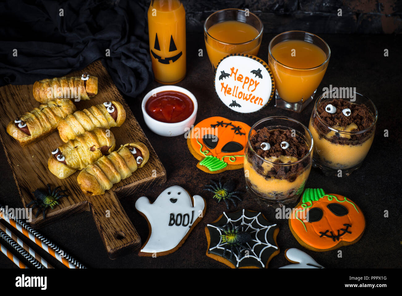 Halloween food assortment - sasage mummies, pumpkin dessert, gin Stock Photo