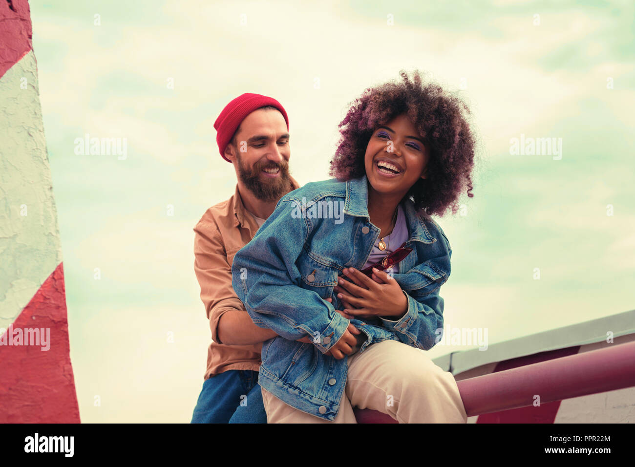 Emotional young girl laughing while positive boyfriend holding her Stock Photo