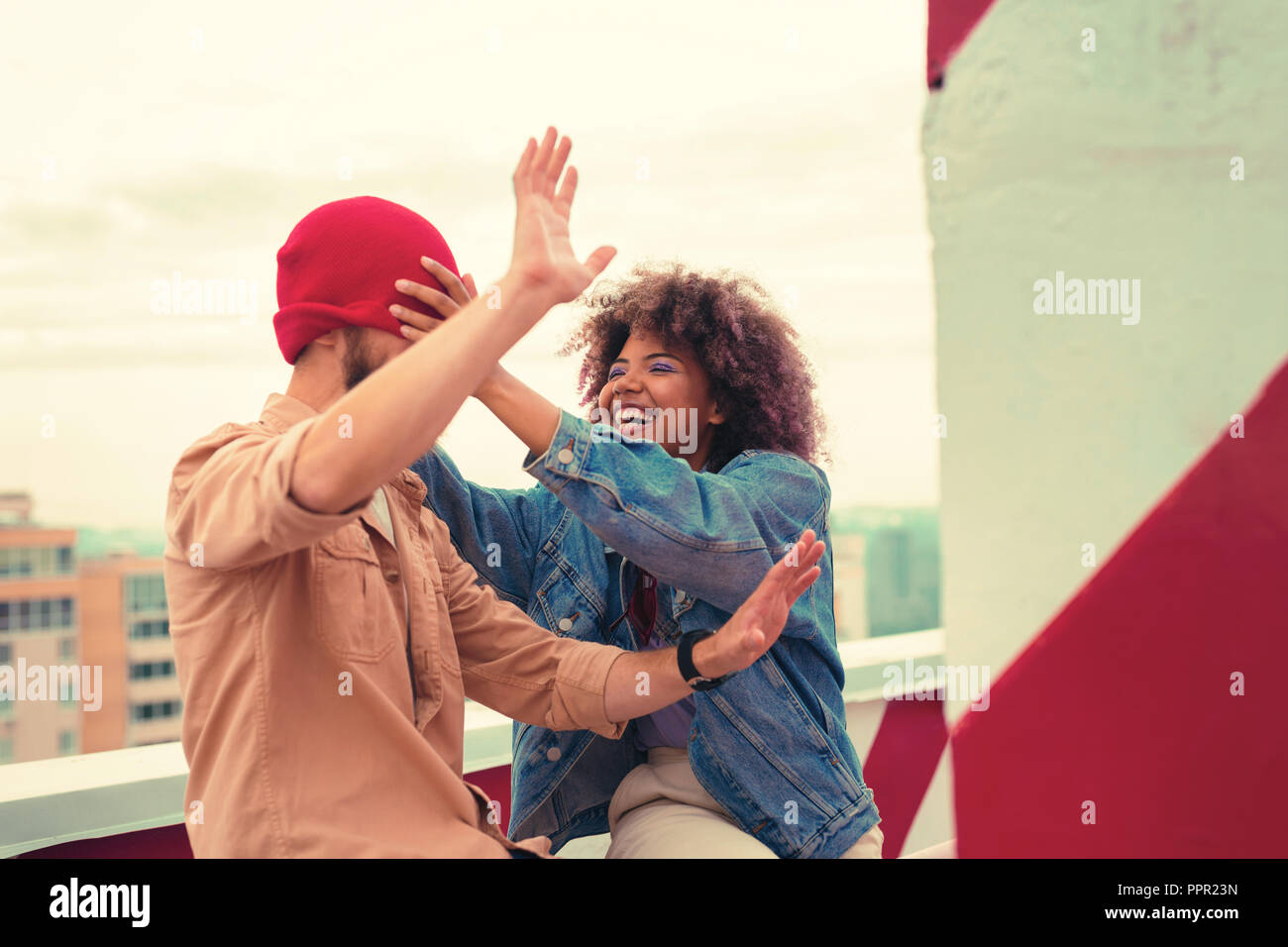 Young girl having fun and pulling the hat on the eyes of her boyfriend Stock Photo