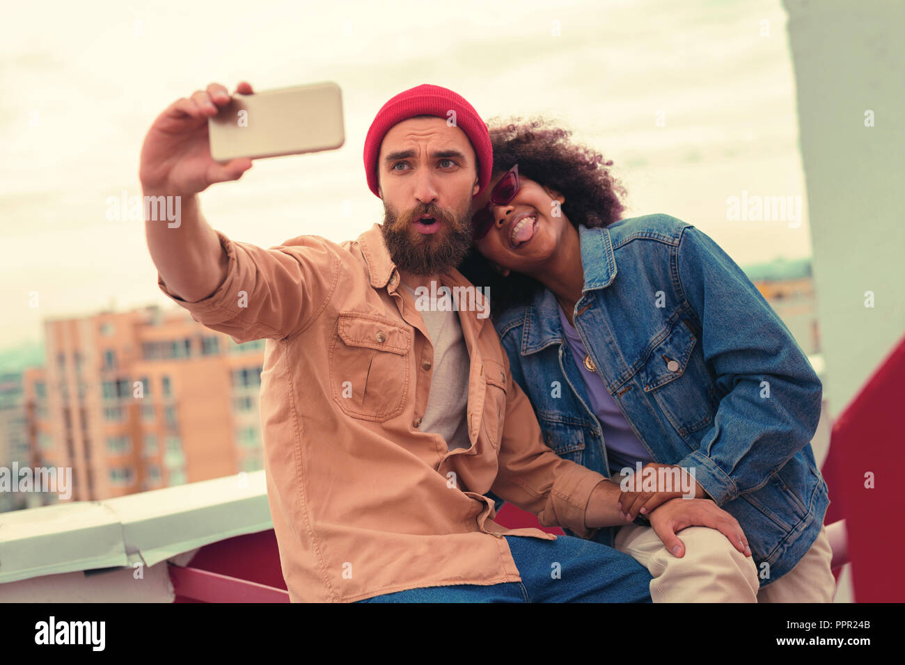 Playful young couple making silly faces while taking selfies Stock Photo