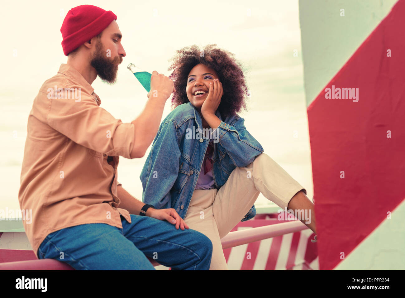 Young man drinking from bottle and girlfriend looking at him Stock Photo