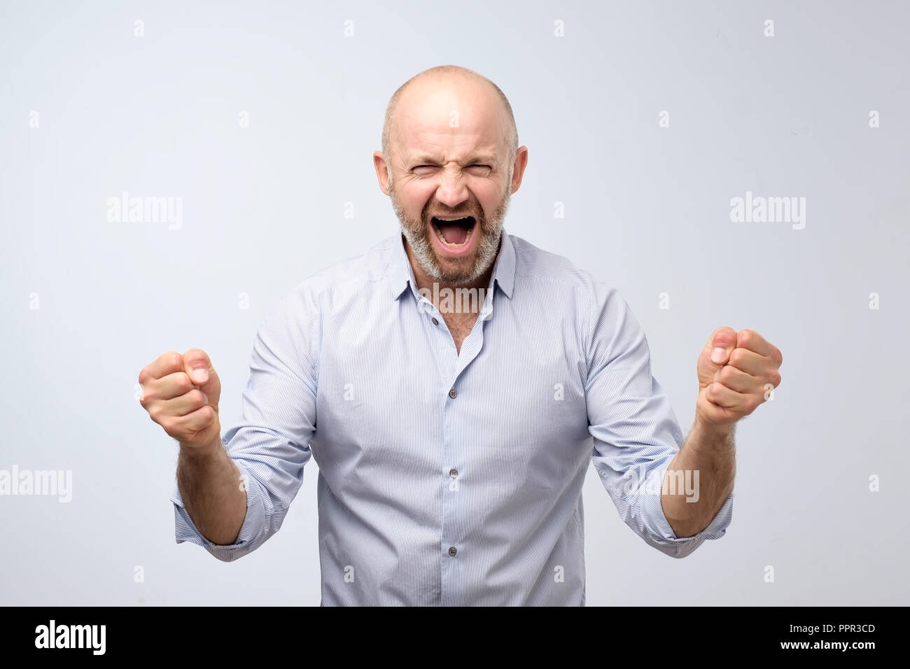 Emotions of a television fan. Shouting emotional angry man screaming holding fists up. Emotional, mature face. Stock Photo