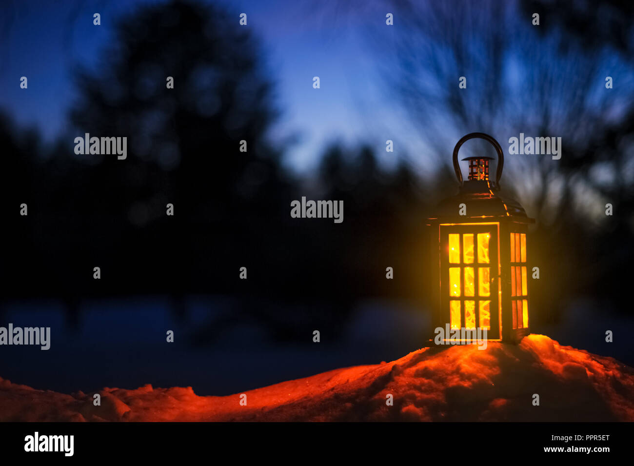 Lantern with Christmas lights in snow. Stock Photo