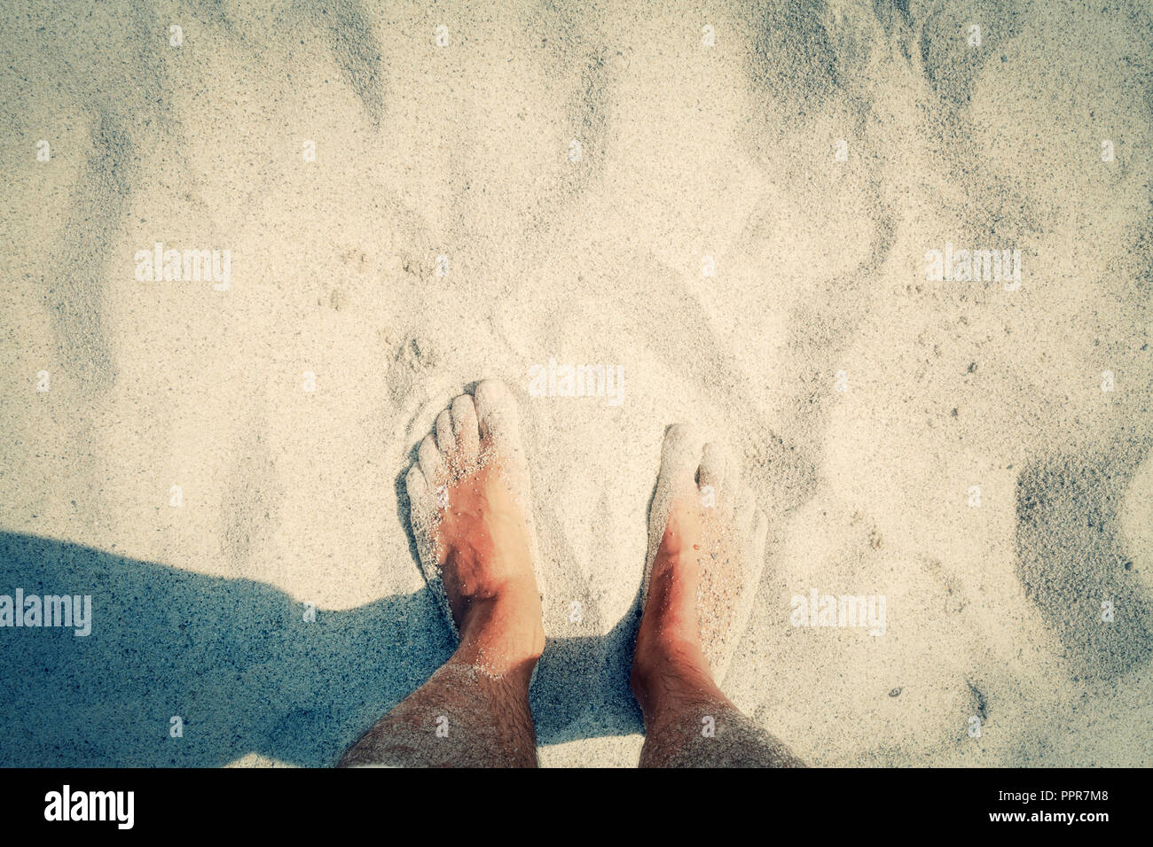 POV of a naked men's feet on the beach, touching the warm sand. Copyspace on the upper part. Mojo colors. Stock Photo
