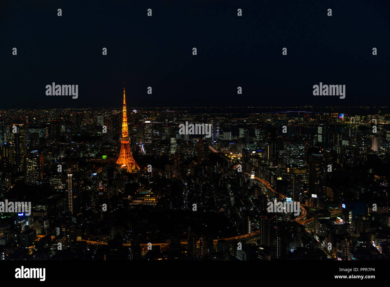 Cityscape of Tokyo at night, as seen from the top of one of the highest buildings in Roppongi Hills, with the illuminated Tokyo Tower glowing. Stock Photo