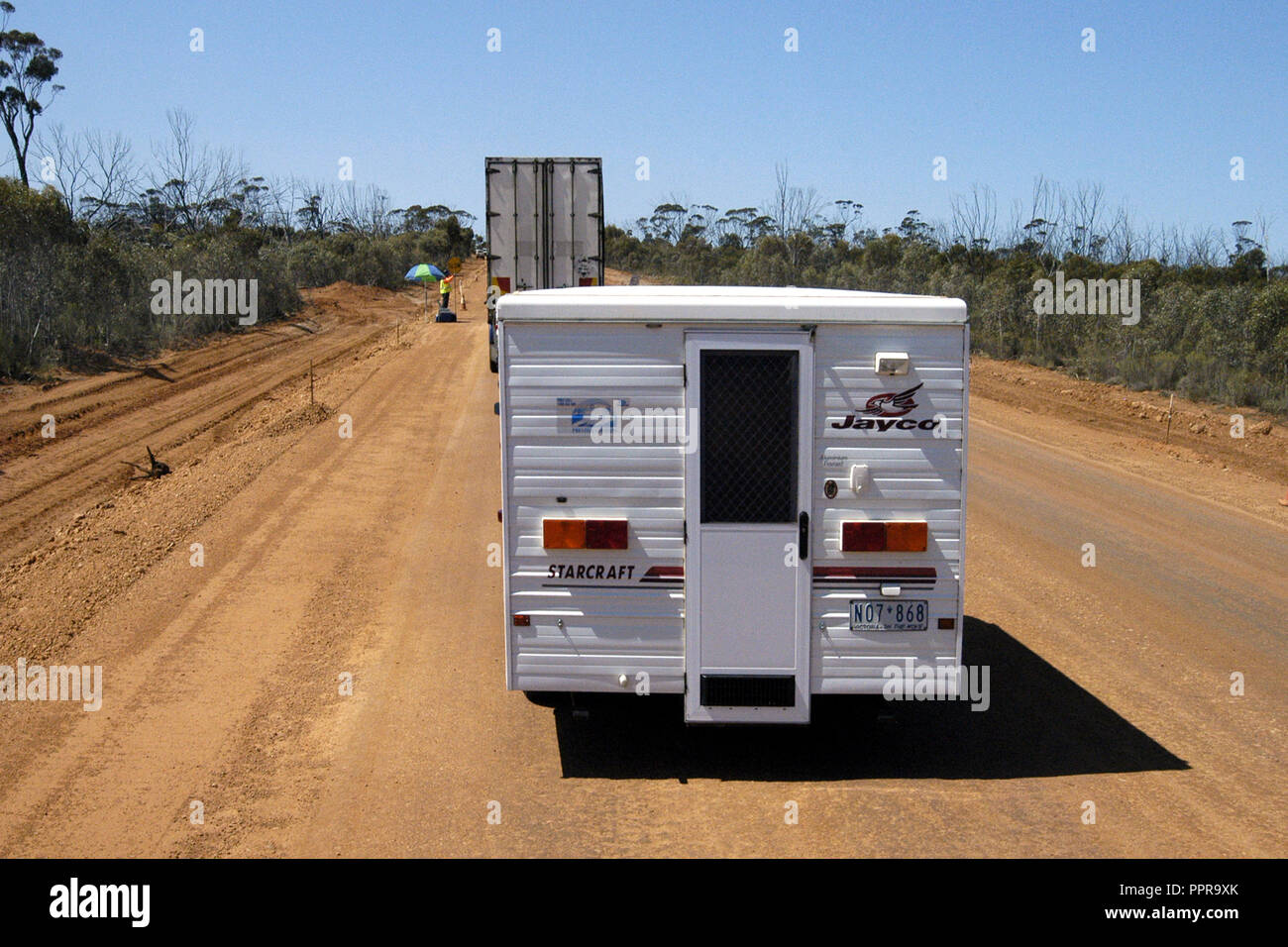 A CARAVAN AND LARGE TRUCK STOPPED TO ALLOW TRAFFIC TO PASS FROM THE OPPOSITE DIRECTION DURING ROADWORKS IN OUTBACK AUSTRALIA Stock Photo
