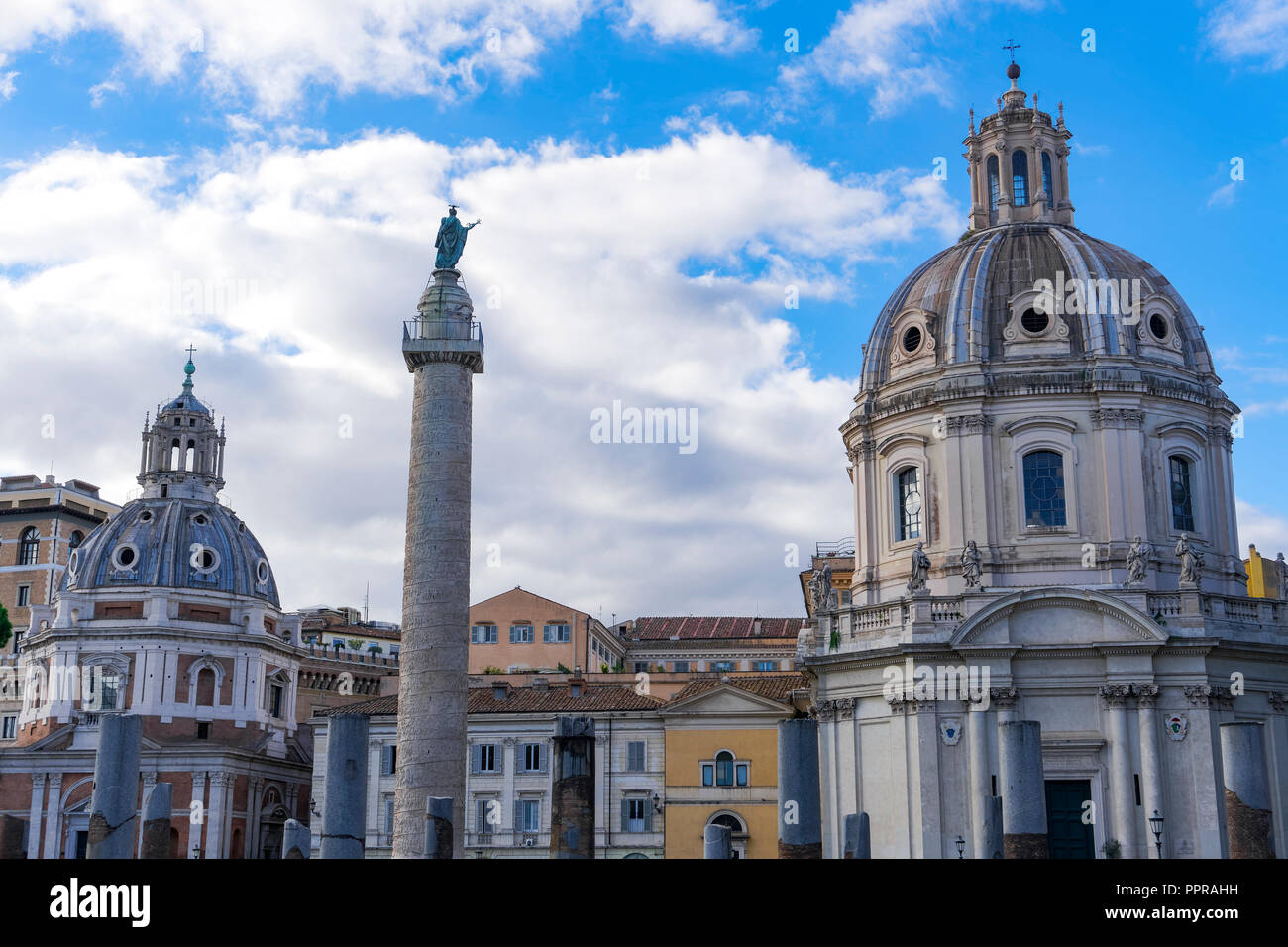 Rome, Italy Trajan triumphal column on Roman Forum. Freestanding marble Colonna Traiana on pedestal with Roman Catholic churches rooftops background. Stock Photo