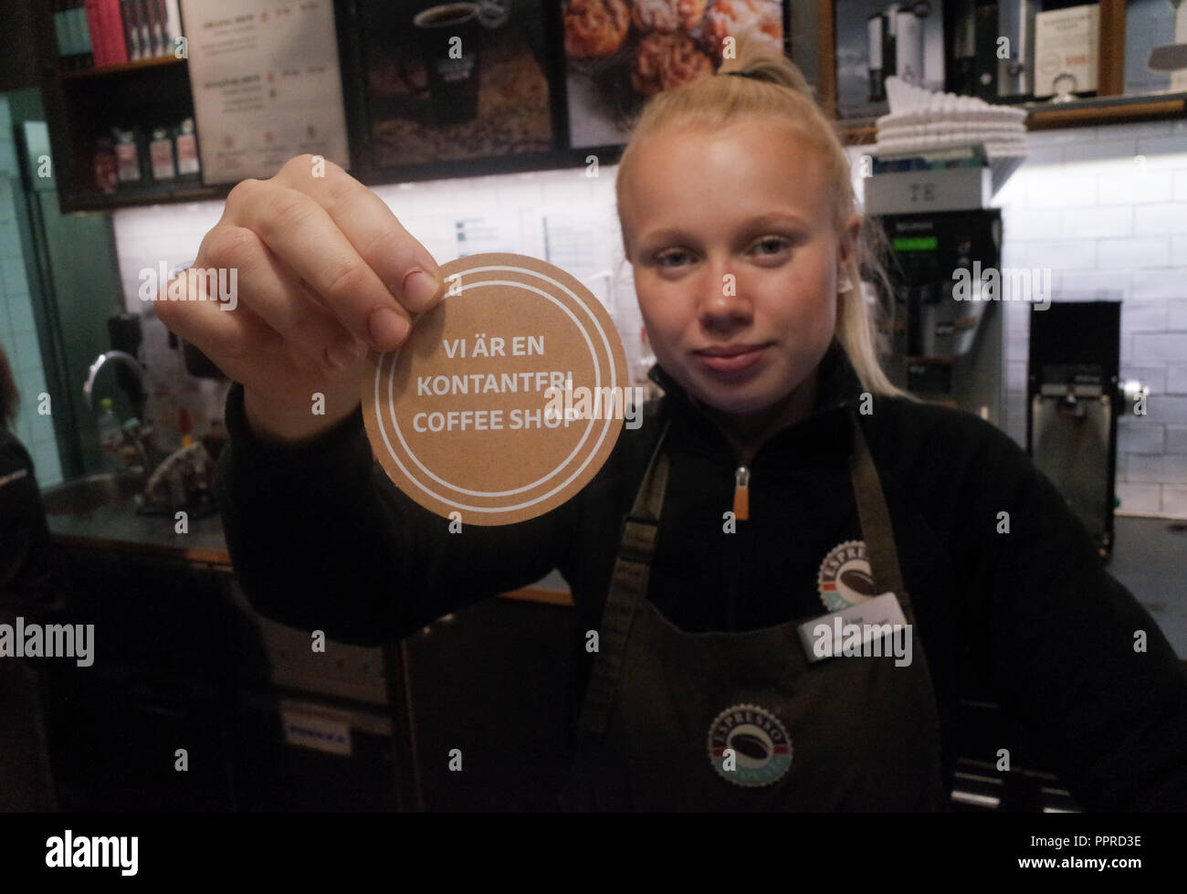 September 26, 2018 - Stockholm, Sweden: An employee of Expresso House shows a sign in Swedish language that means 'We Are a Cashless Coffee shop'. Sweden is the most cashless society on the planet, with 80% of all transactions in made with bank cards or mobile phone apps. *** FRANCE OUT / NO SALES TO FRENCH MEDIA *** Stock Photo