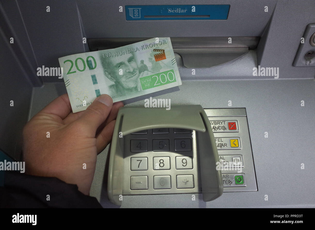 September 26, 2018 - Stockholm, Sweden: A man withdraws a 200 krona  banknote from an ATM. Sweden is the most cashless society on the planet,  with 80% of all transactions in made