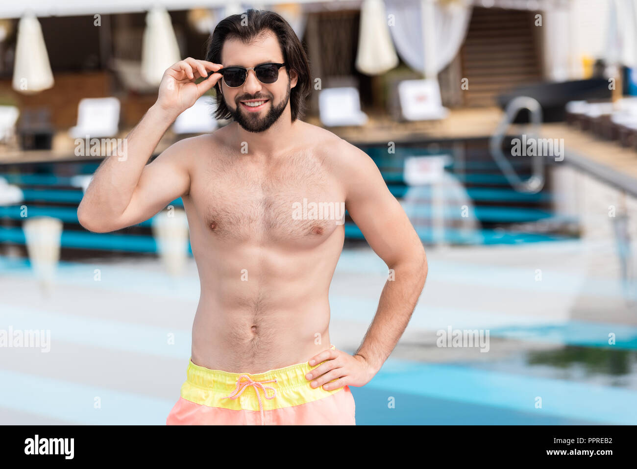 handsome bearded man in sunglasses posing at swimming pool Stock