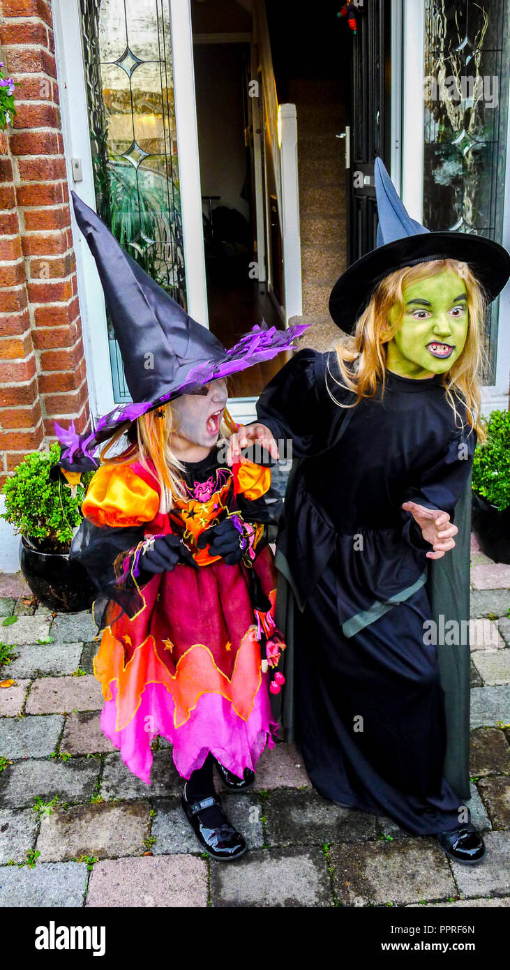 Little girls children dressed in Witches Halloween costume, wearing black witch hat, dresses, witch costume Stock Photo