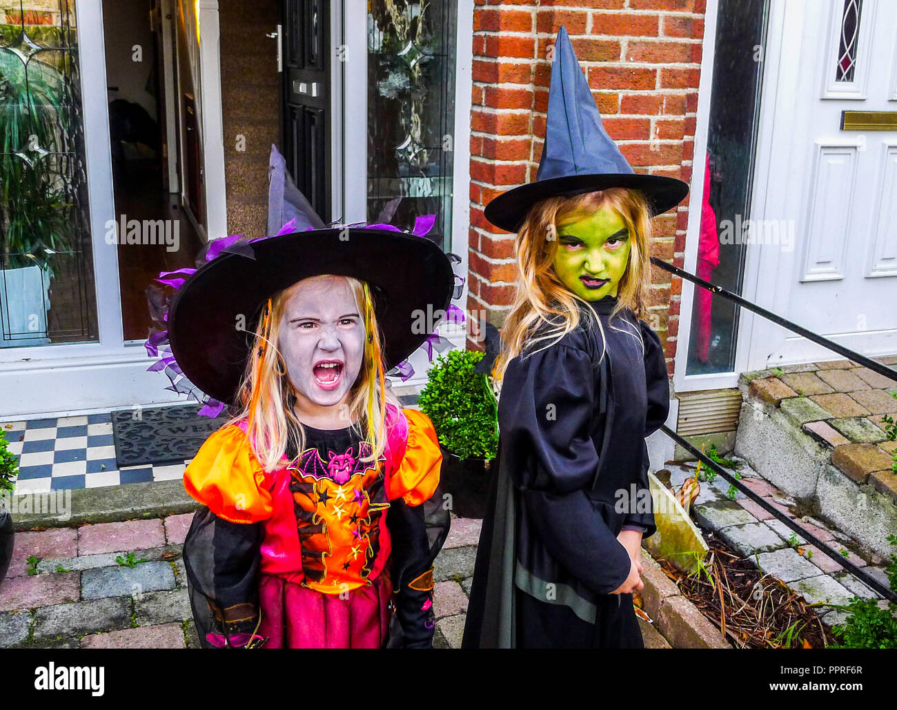 Little girls children dressed in Witches Halloween costume, wearing black witch hat, dresses, kids halloween costume, witch costume Stock Photo