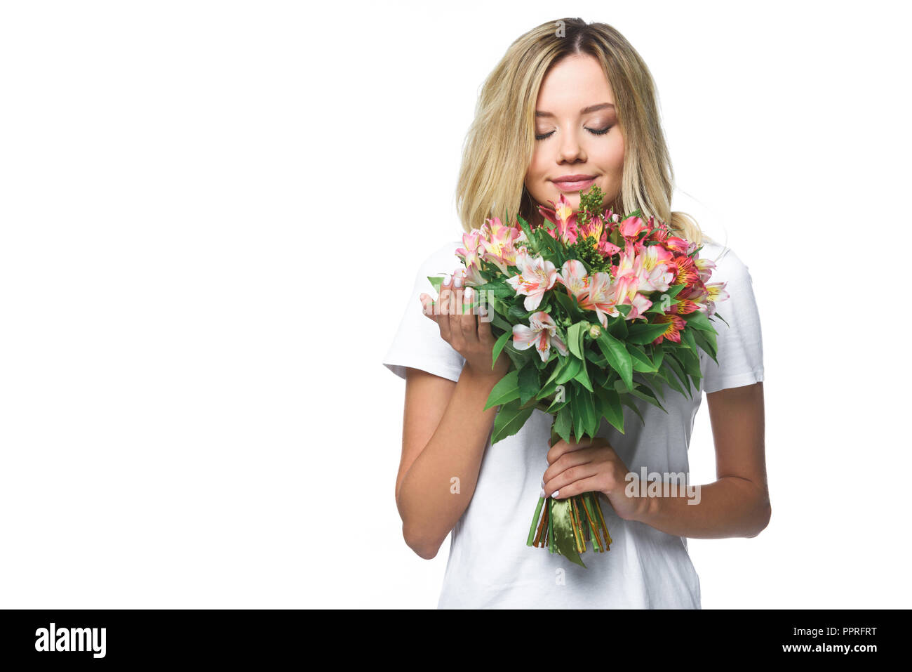 attractive girl in white shirt sniffing bouquet of flowers with closed eyes isolated on white Stock Photo