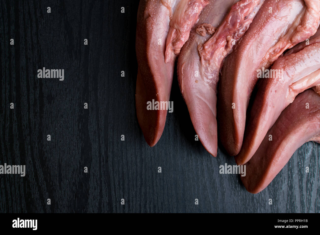raw pork or beef tongues on black wooden, gourment food conception